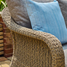 Close-up of a textured chair with a blue cushion and woven armrest.