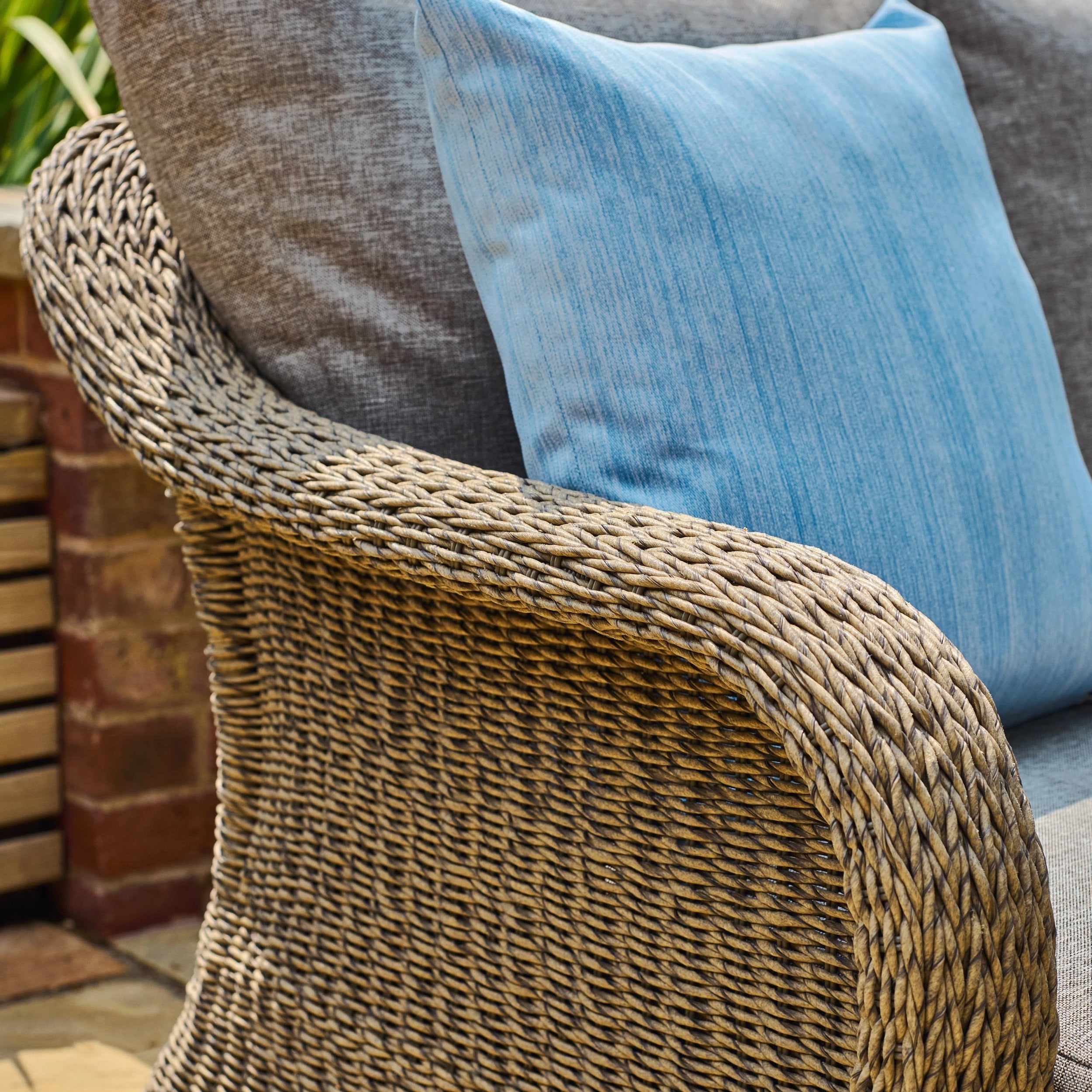 Close-up of a textured chair with a blue cushion and woven armrest.