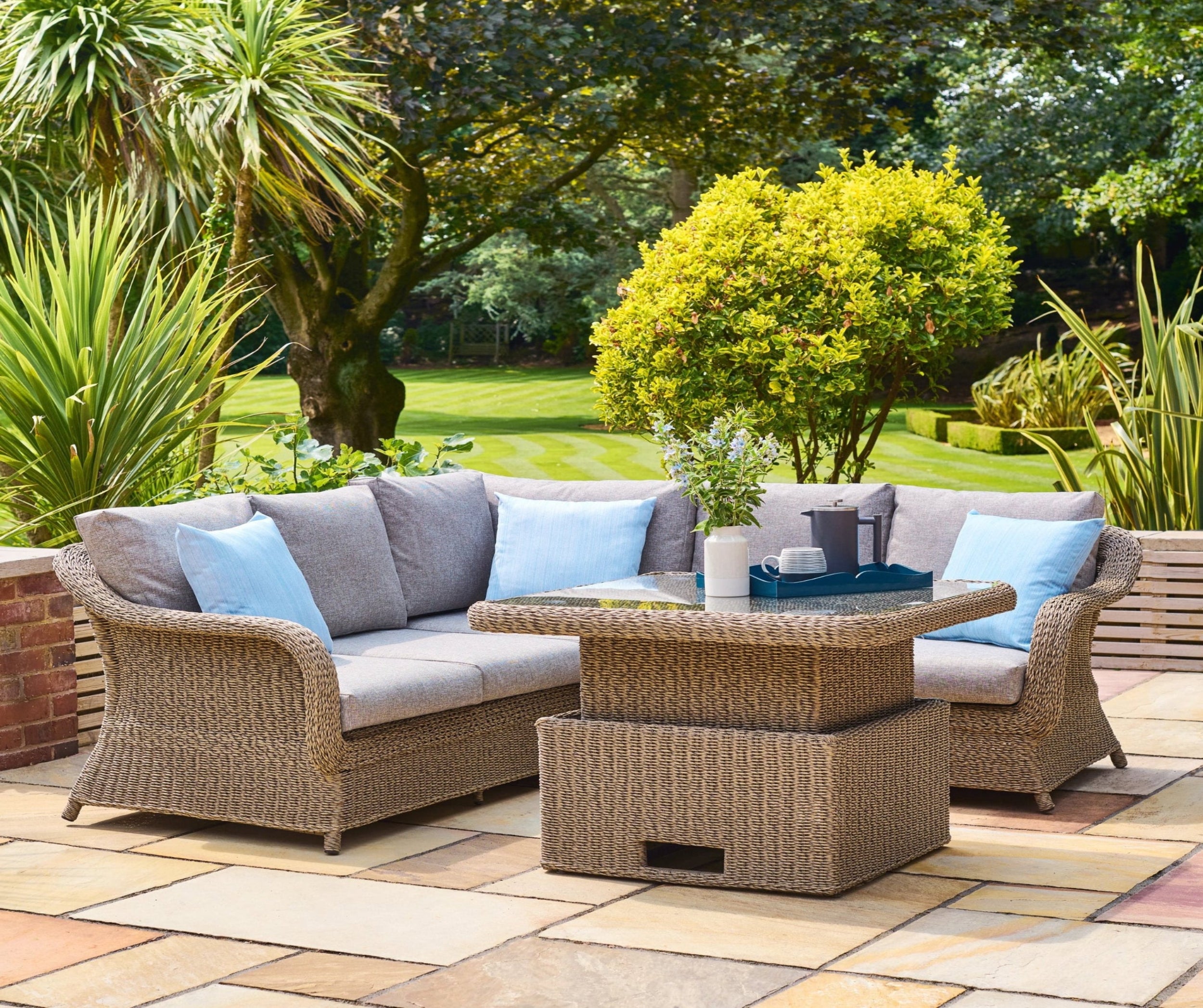 Outdoor patio set with wicker furniture and cushions on a paved patio area.