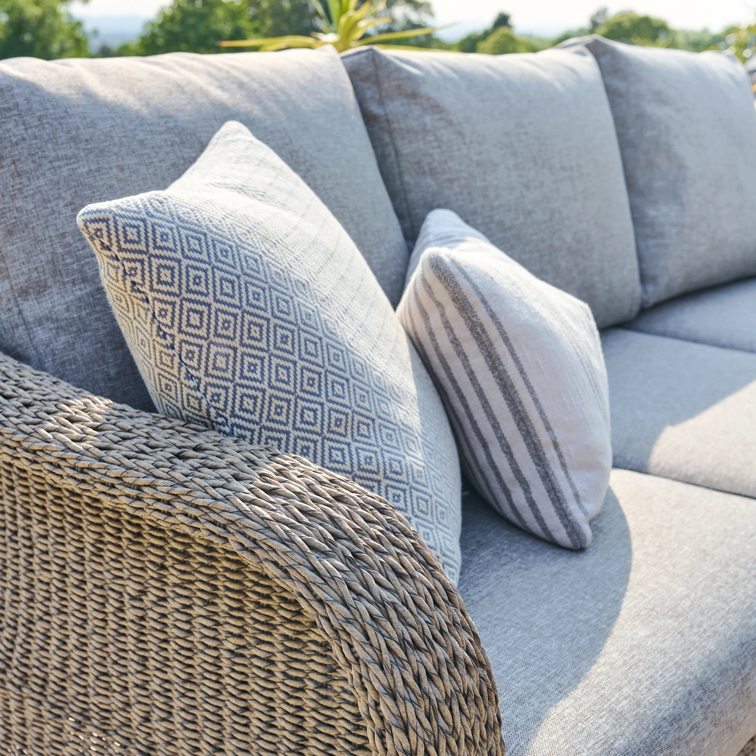 Gray outdoor sofa with patterned cushions and a woven armchair.