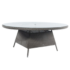 Round outdoor table with wicker frame and glass top on a white background