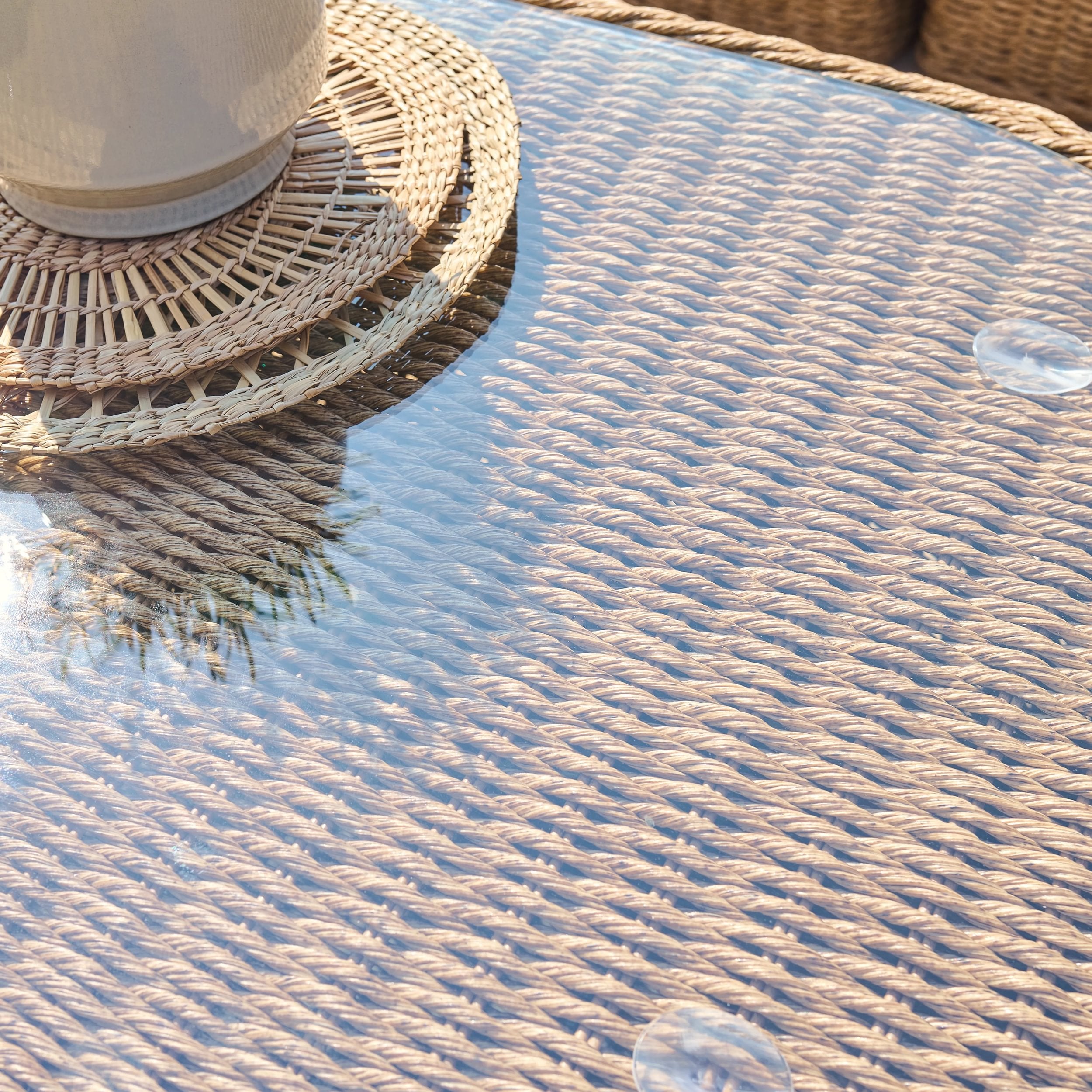wicker table detail with glass top and woven coaster with white tea cup