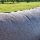 Close-up of a textured gray cushion with a blurred green field in the background