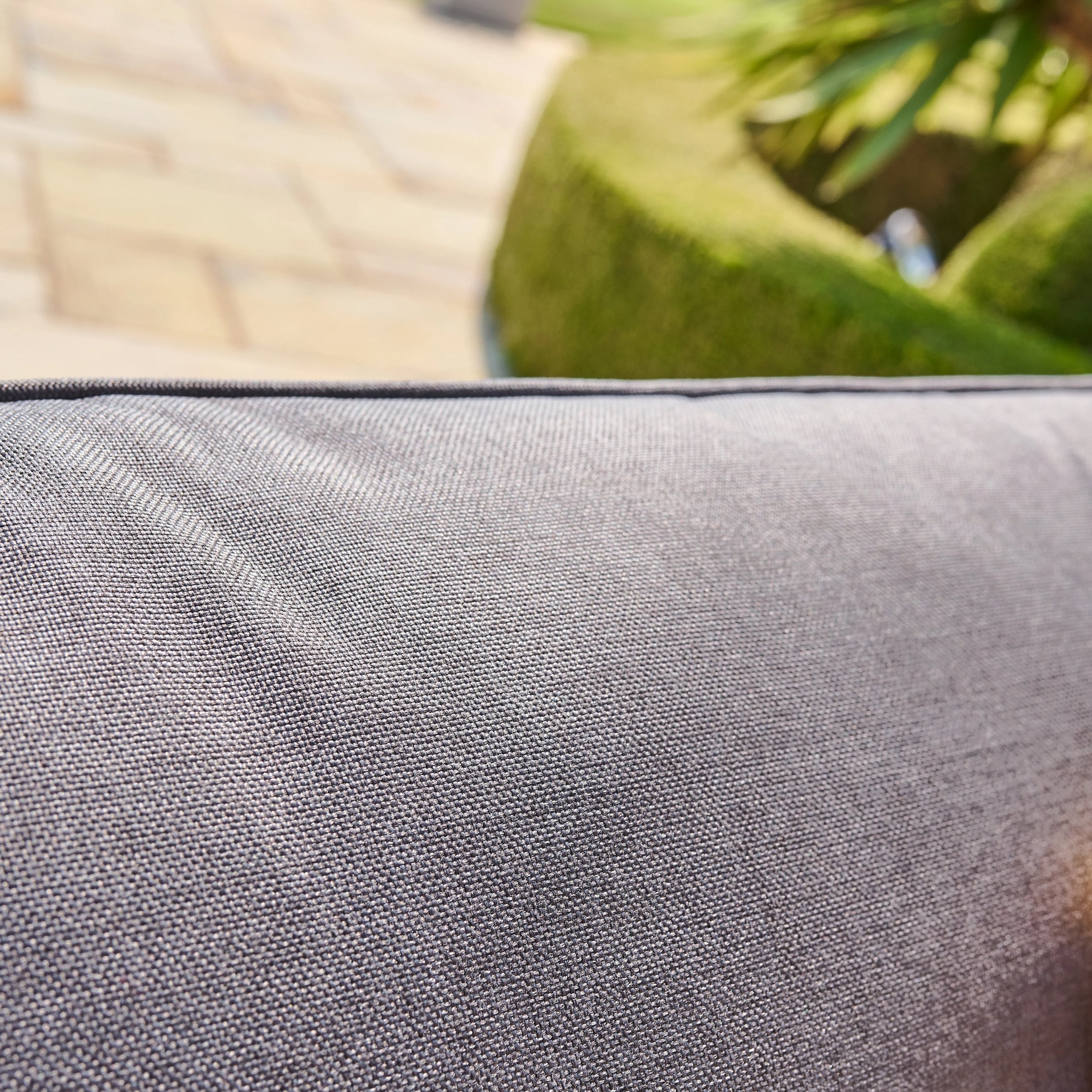 Close-up of a textured gray cushion with a blurred natural background