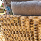 Woven armchair rest with textured cushions on a blurred outdoor background