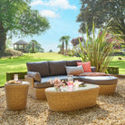 Outdoor patio set with a sofa, ottoman, and coffee table in a garden setting.