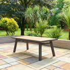 Outdoor patio table on a stone patio with greenery in the background