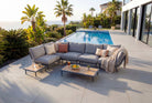 Outdoor patio set with sectional sofa, coffee table, and cushions by a poolside.