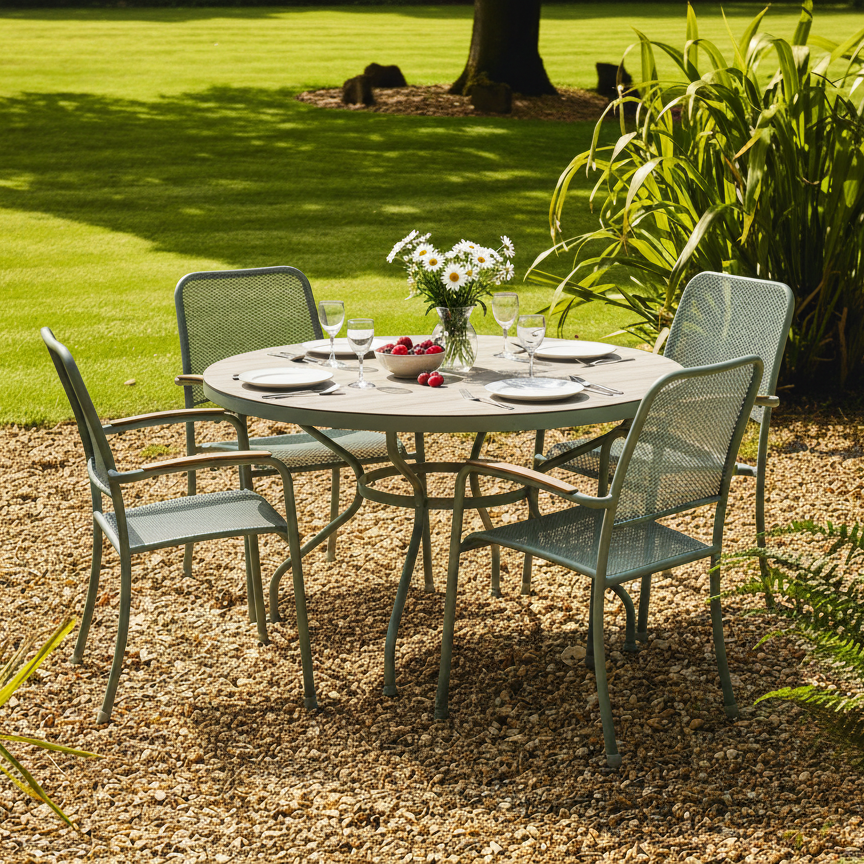Outdoor garden setting with a round table and chairs on a gravel path, surrounded by greenery.
