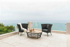 2 high back cordial dark grey chairs by Alexander Rose on a patio overlooking the sea