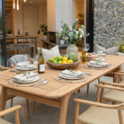 Dining table set with plates, glasses, and a bowl of fruit in a modern living room.