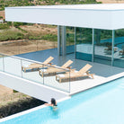 overhead view of 3 roble sun loungers on a patio area with a white building in the background an a pool in the foreground
