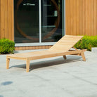 wood sun lounger on a patio in front of a garden room