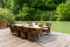 Teak rectangular dining table with luxury rattan armchair's besides a lake