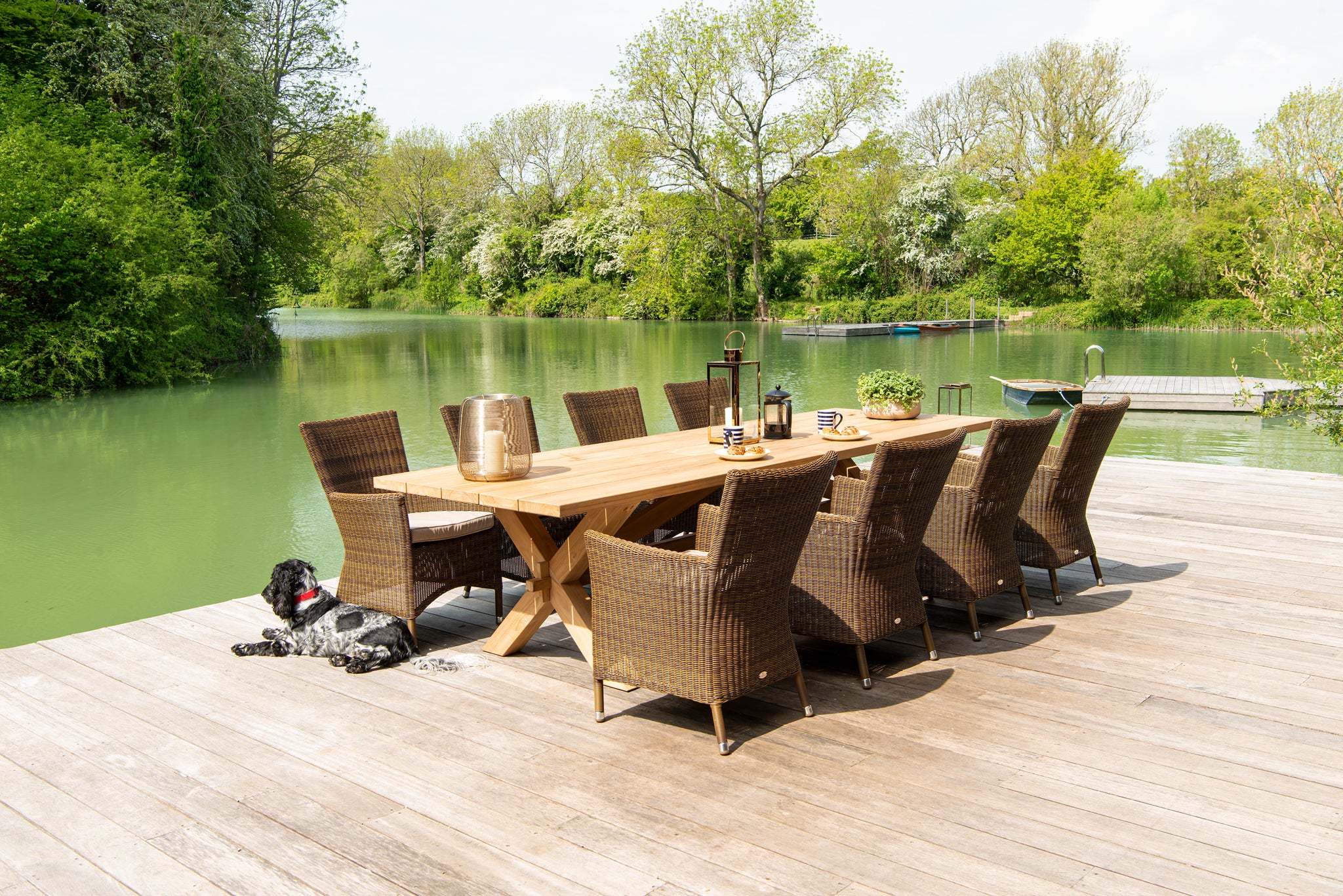 Large Plank Teak rectangular dining table with luxury rattan armchair's shown on an outdoor patio