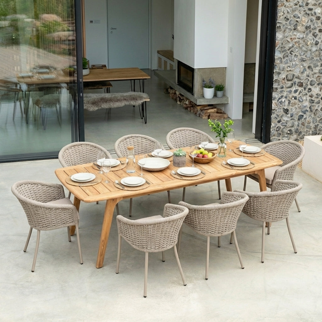 Wooden outdoor dining table with rope-woven chairs set up for a meal, in a modern outdoor living space.