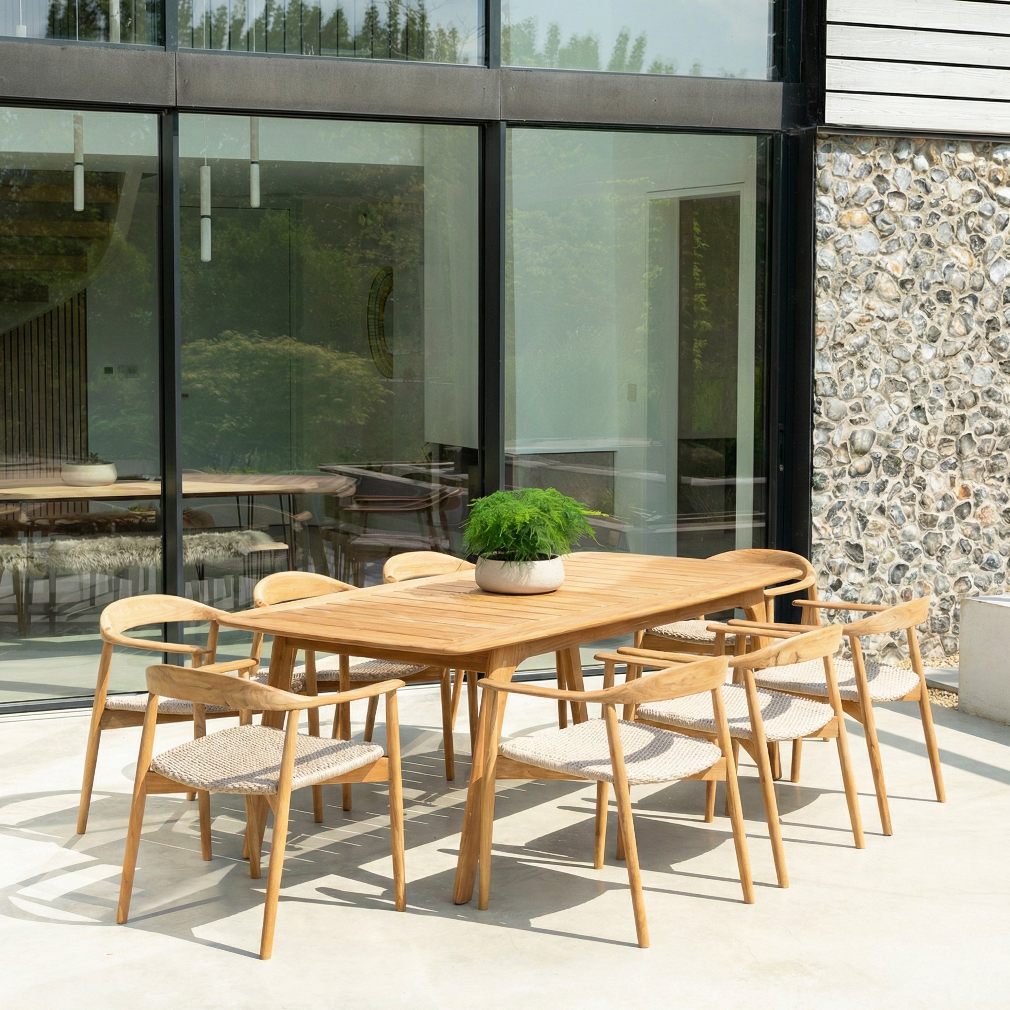 Wooden outdoor dining set with chairs and a table in front of a modern building with large glass windows.
