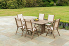6 folding outdoor chairs and a rectangular table on a patio near a lawn