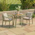 Outdoor patio set with two chairs and a table on a stone patio, surrounded by greenery.