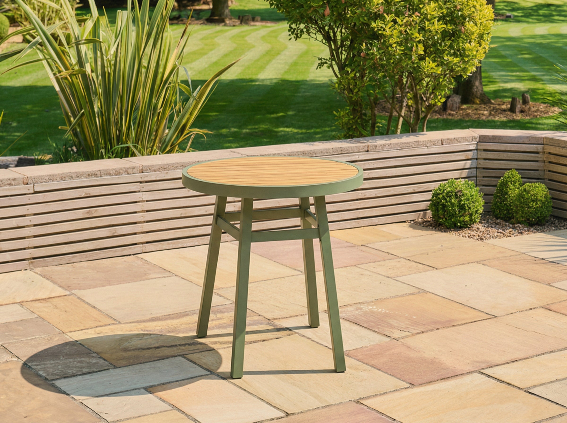Green outdoor stool on a patio with grass and plants in the background