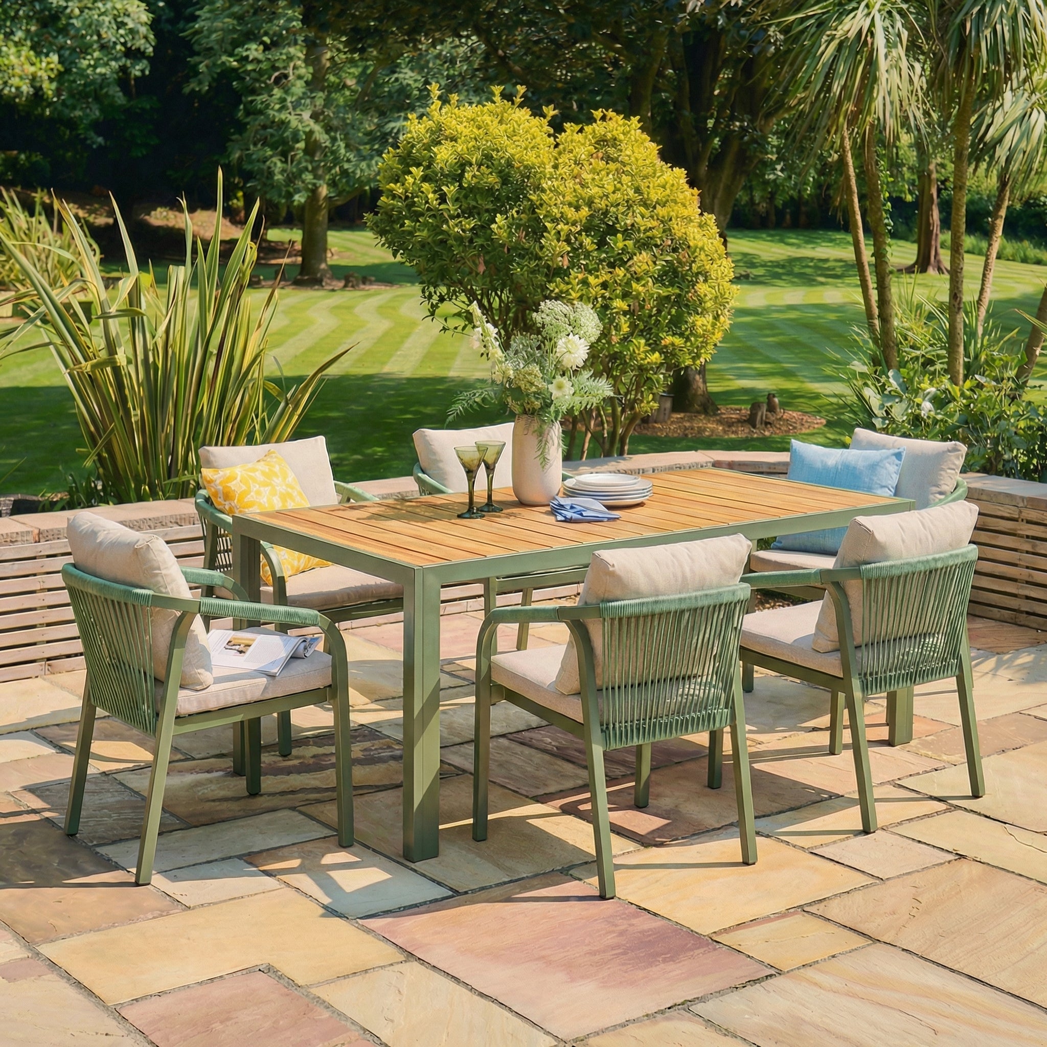 Outdoor patio set with a wooden table and green chairs on a stone patio.