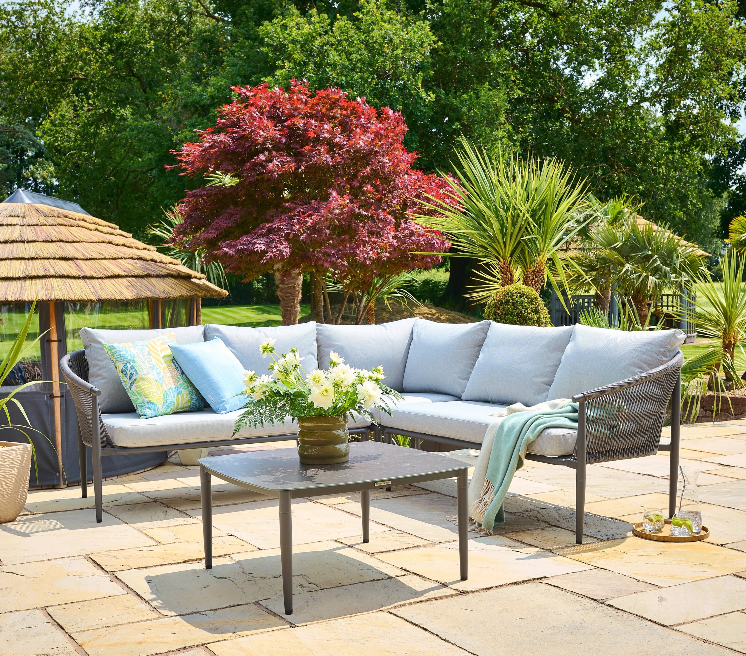 Outdoor patio with a sectional sofa, coffee table, and decorative elements on a stone patio.