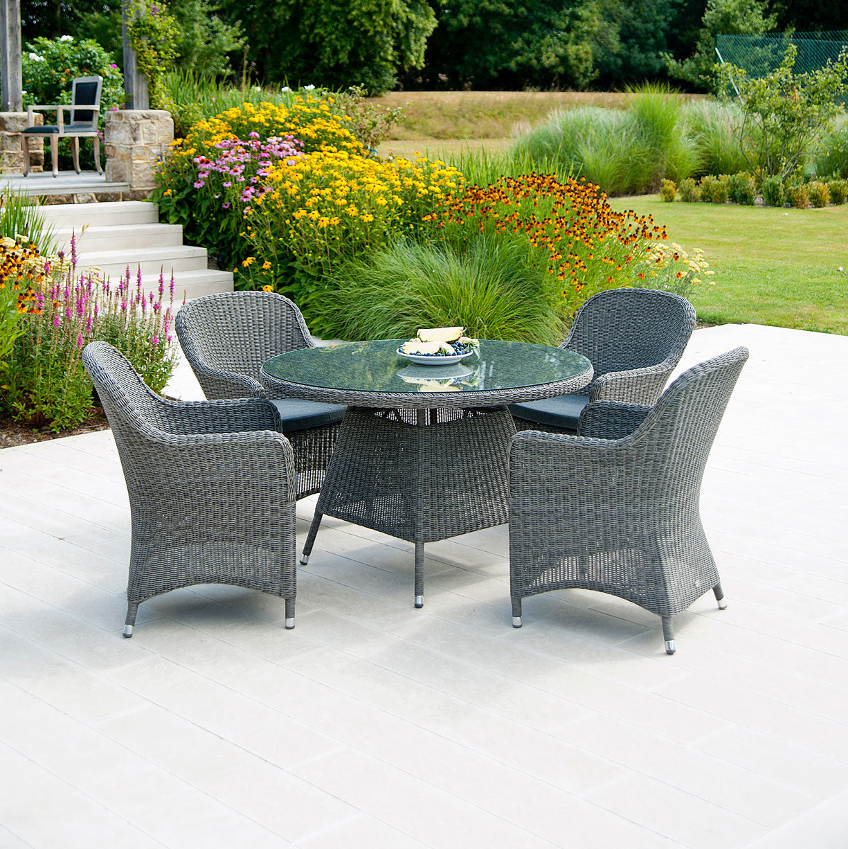 Alexander Rose Monte Carlo garden table and 4 chairs in a grey rattan. Circular table. Rounded armchairs.