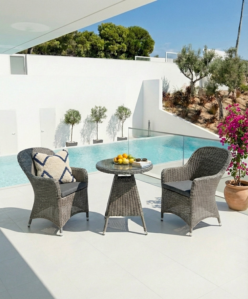 Outdoor patio set with two chairs and a small table by a poolside.