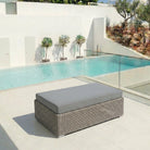 Monte Carlo rattan Ottoman on a terrace beside a swimming pool under natural daylight.