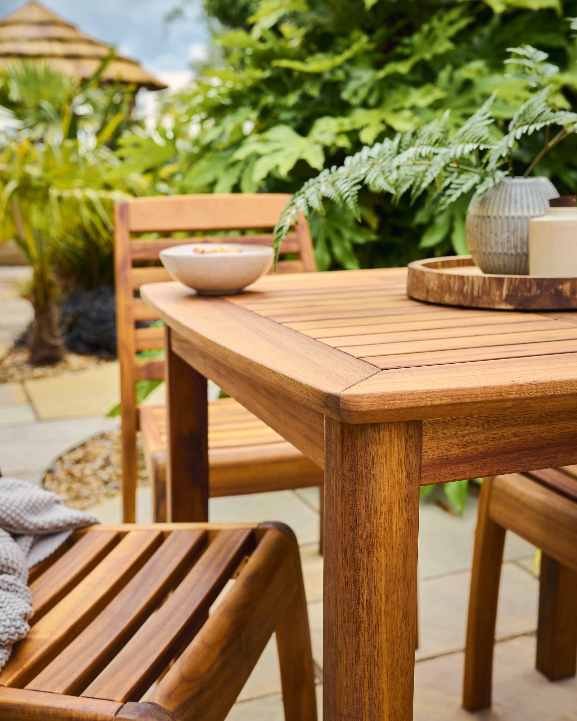 Wooden outdoor dining table and chairs with a garden background