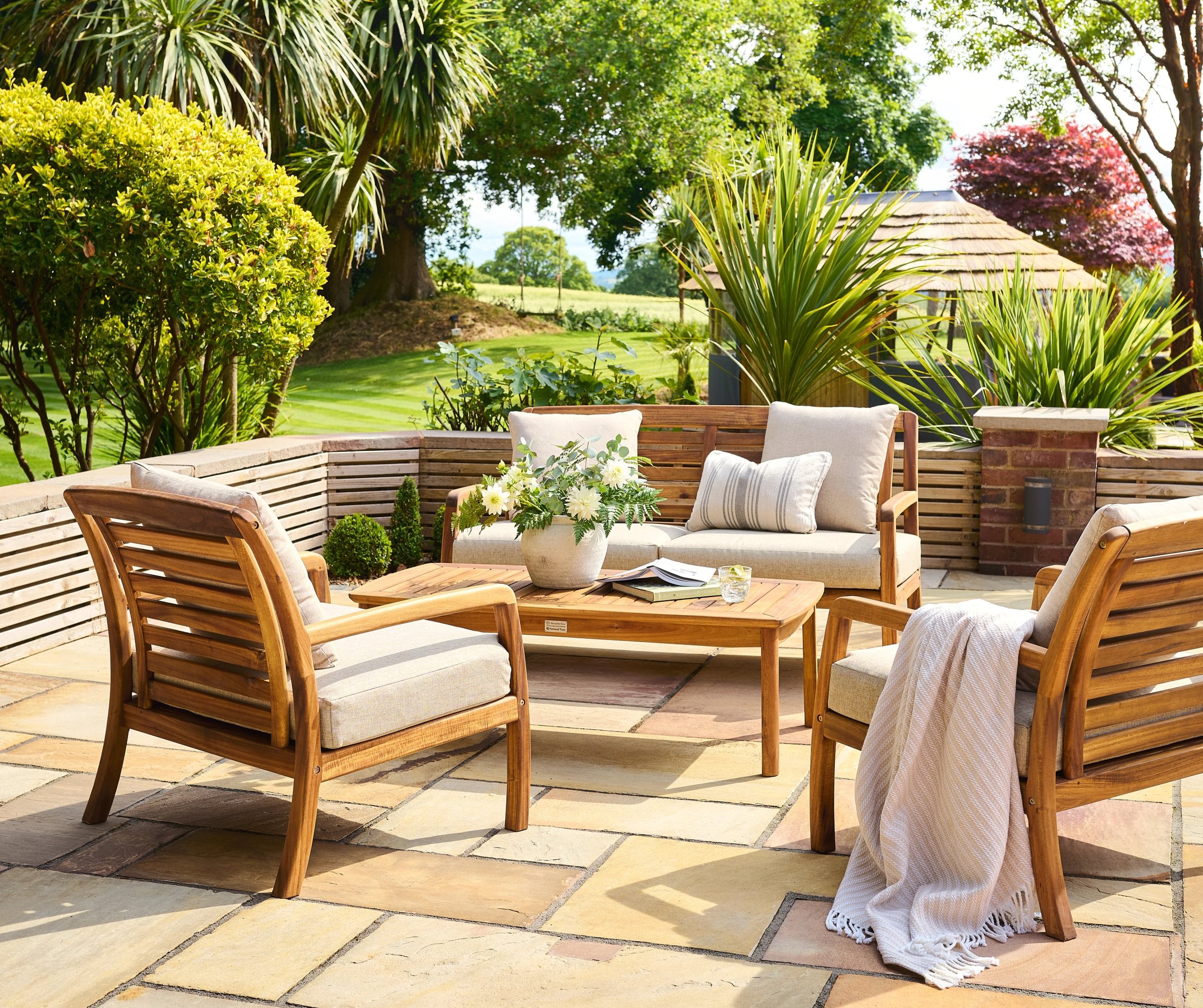 Outdoor patio set with wooden chairs and table in a garden setting