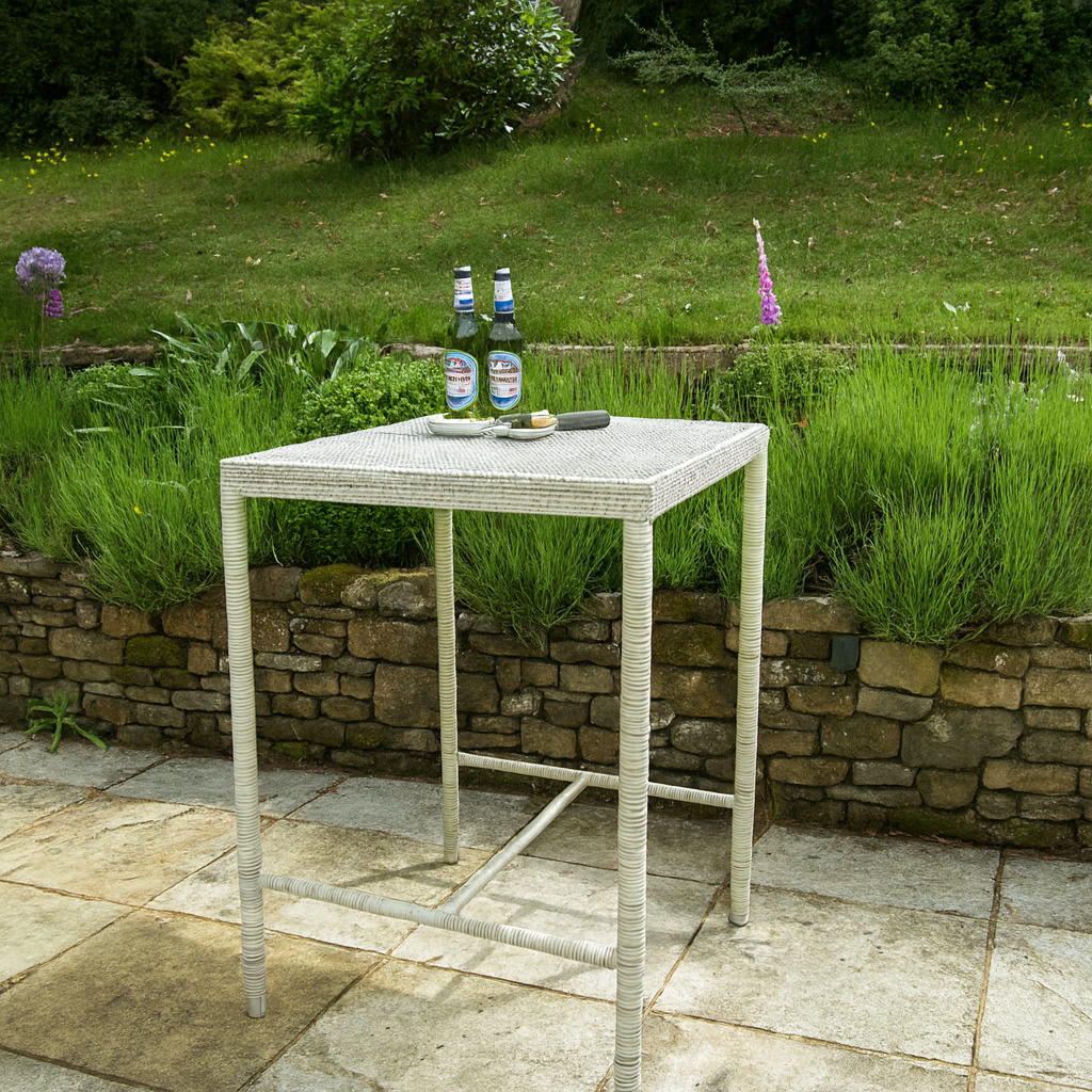 Outdoor setting with a small bar table on a patio, surrounded by greenery and a stone wall.
