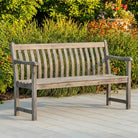Wooden bench on a wooden deck with greenery and flowers in the background