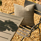 Outdoor chair with a patterned cushion next to a table on a gravel surface