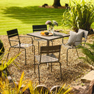 Outdoor patio set with table and chairs in a garden setting