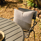 Chair with a patterned cushion on a gravel surface with plants in the background