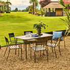 Outdoor patio set with table and chairs on a gravel area, grassy field, and gazebo in the background.