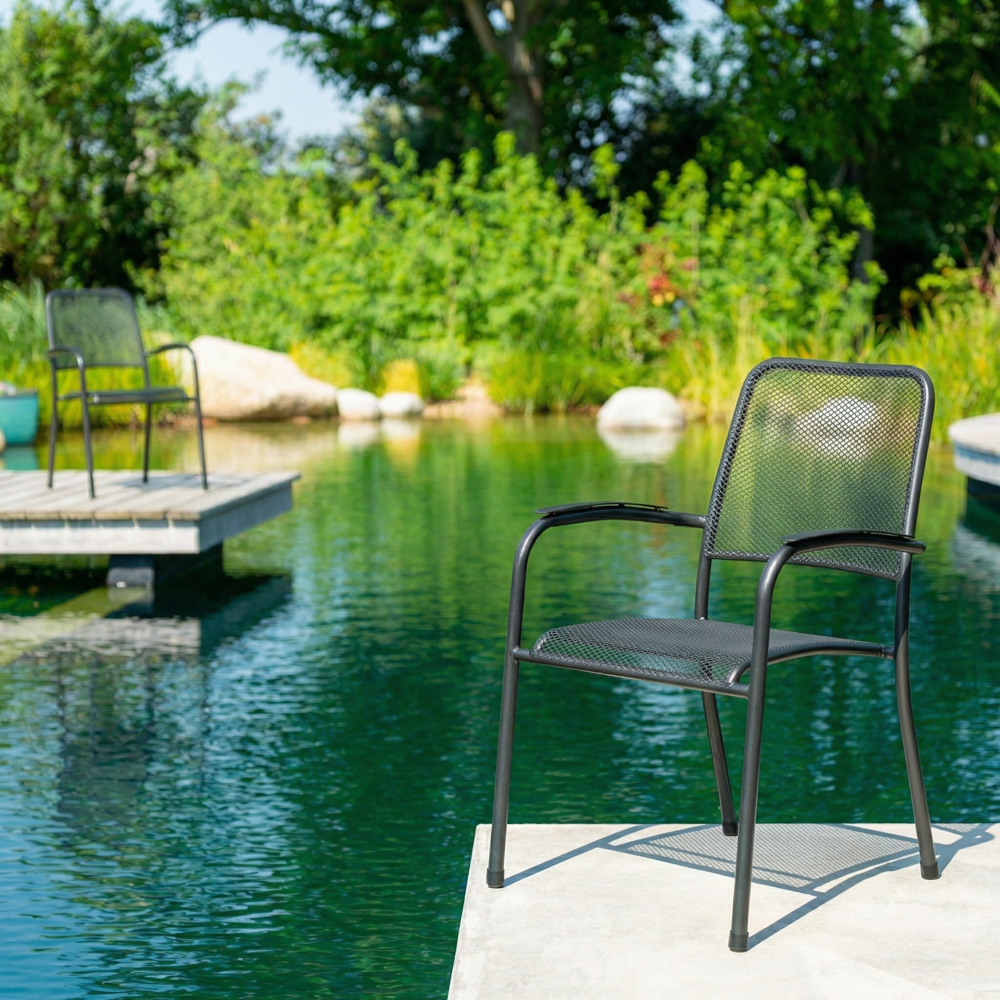 Black metal chair by a pond with greenery in the background