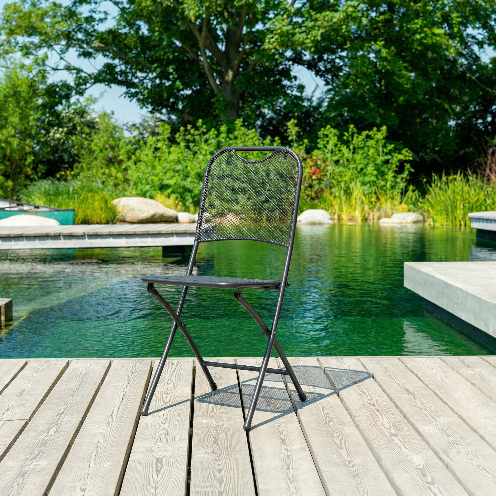 Chair on a wooden deck by a pool with greenery in the background