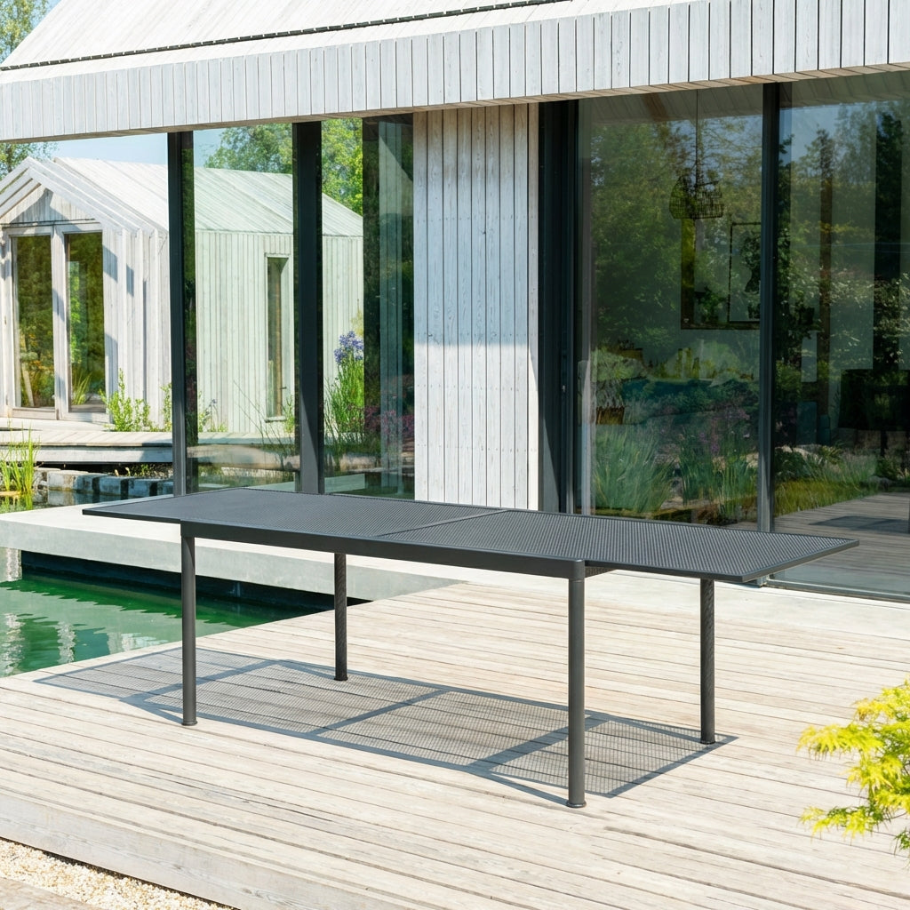 Outdoor dining table on a wooden deck with a modern house and garden in the background