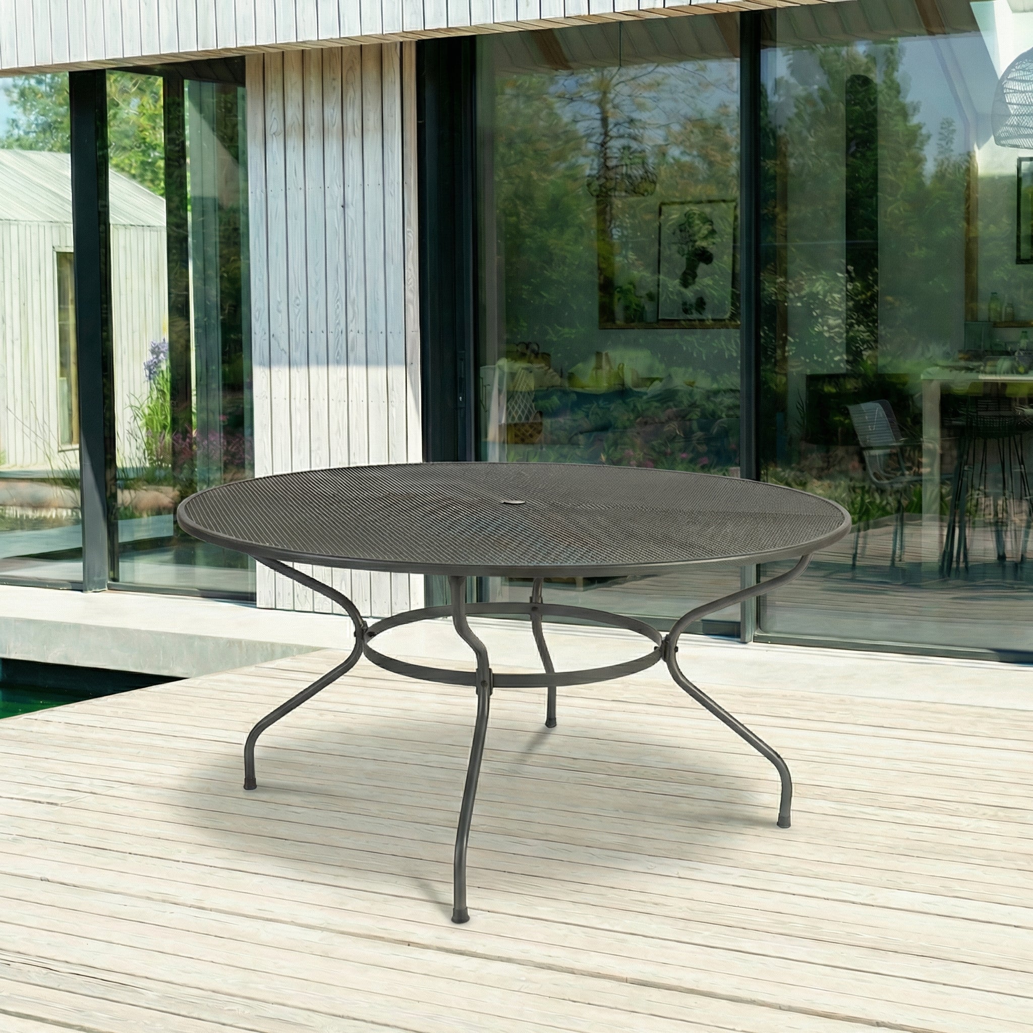Round metal outdoor table on a wooden deck with a modern house in the background