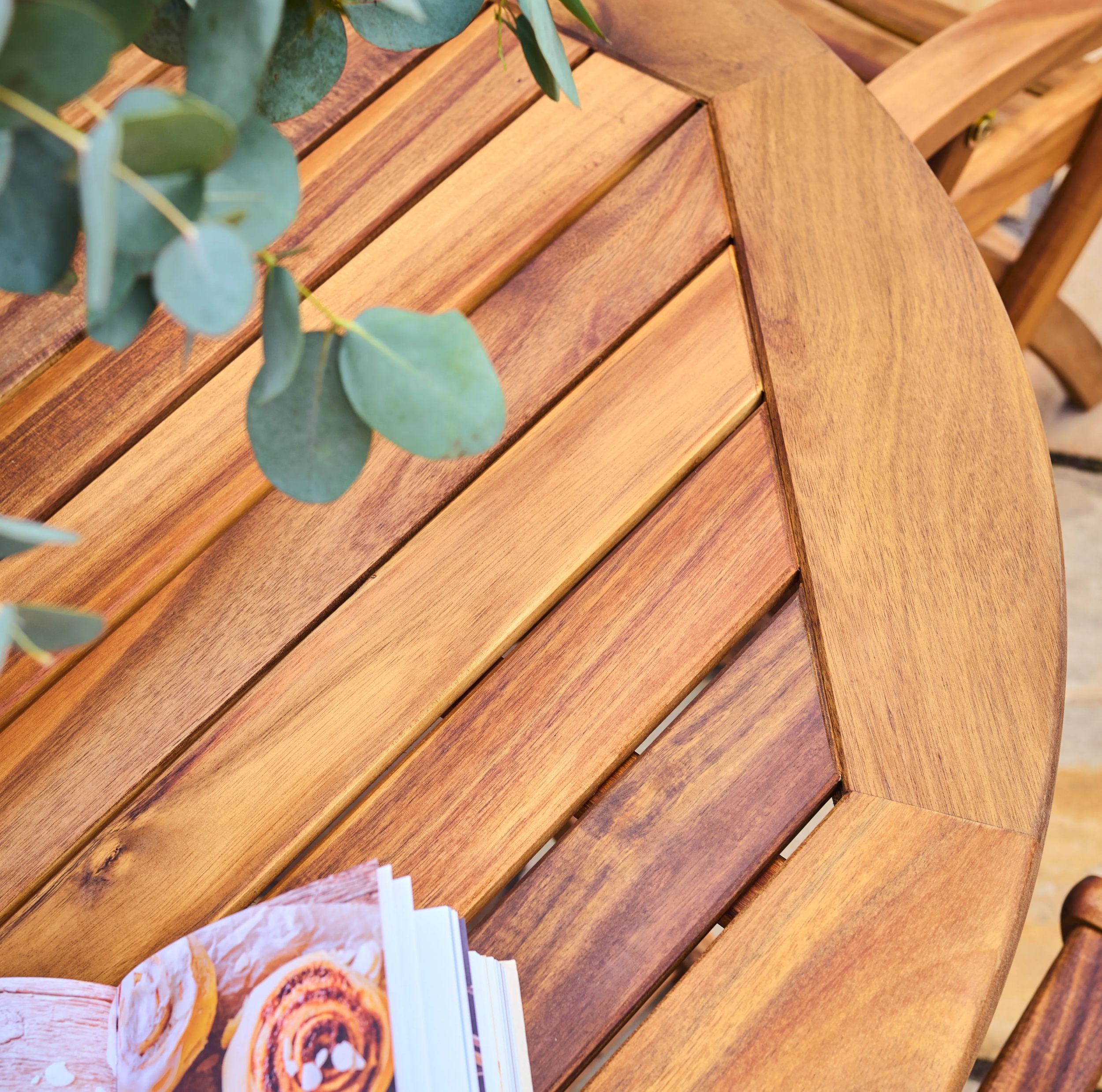 Wooden table with a magazine and green leaves on a blurred background