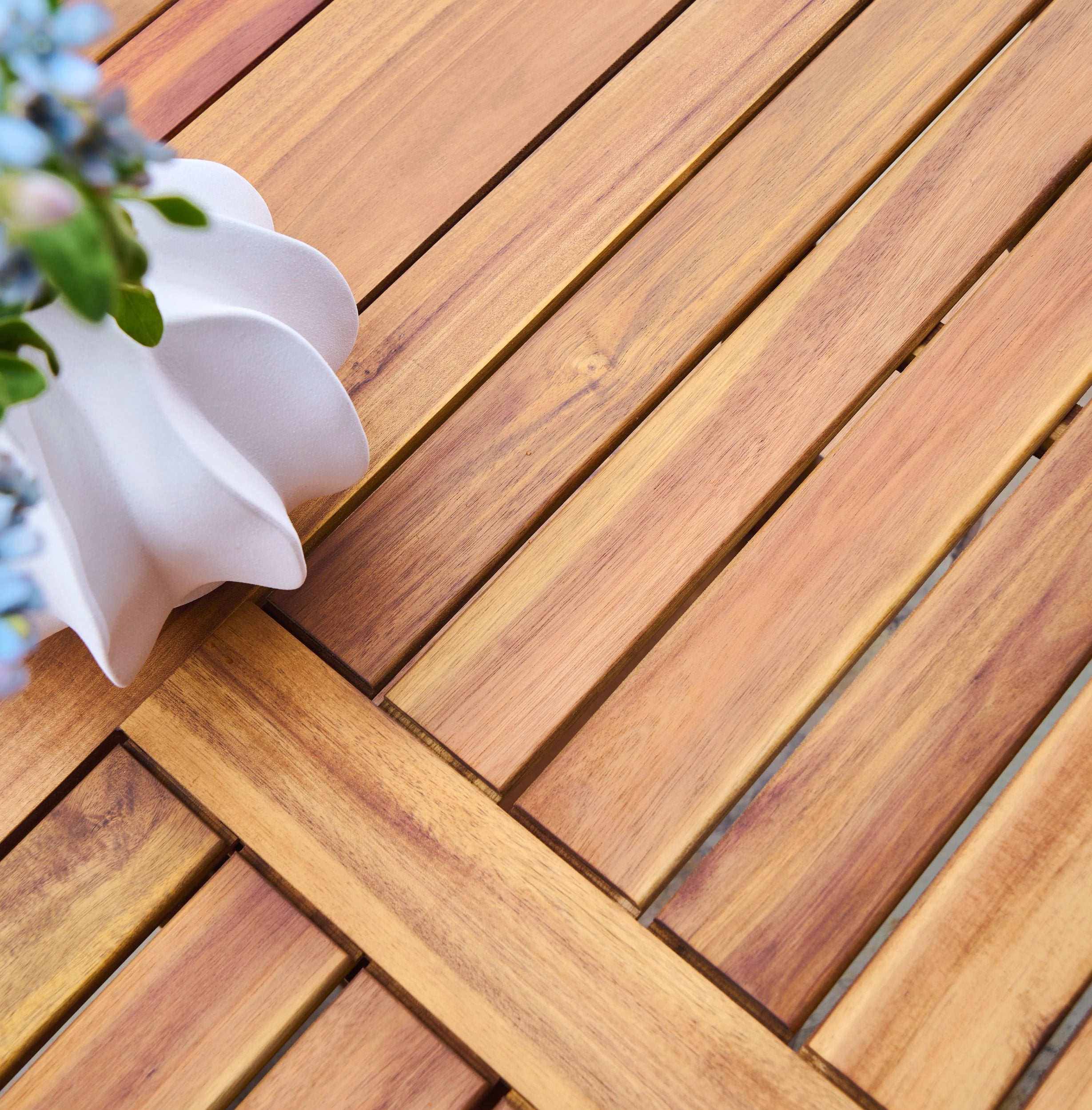 Wooden table with a white ceramic flowerpot and blue flowers.