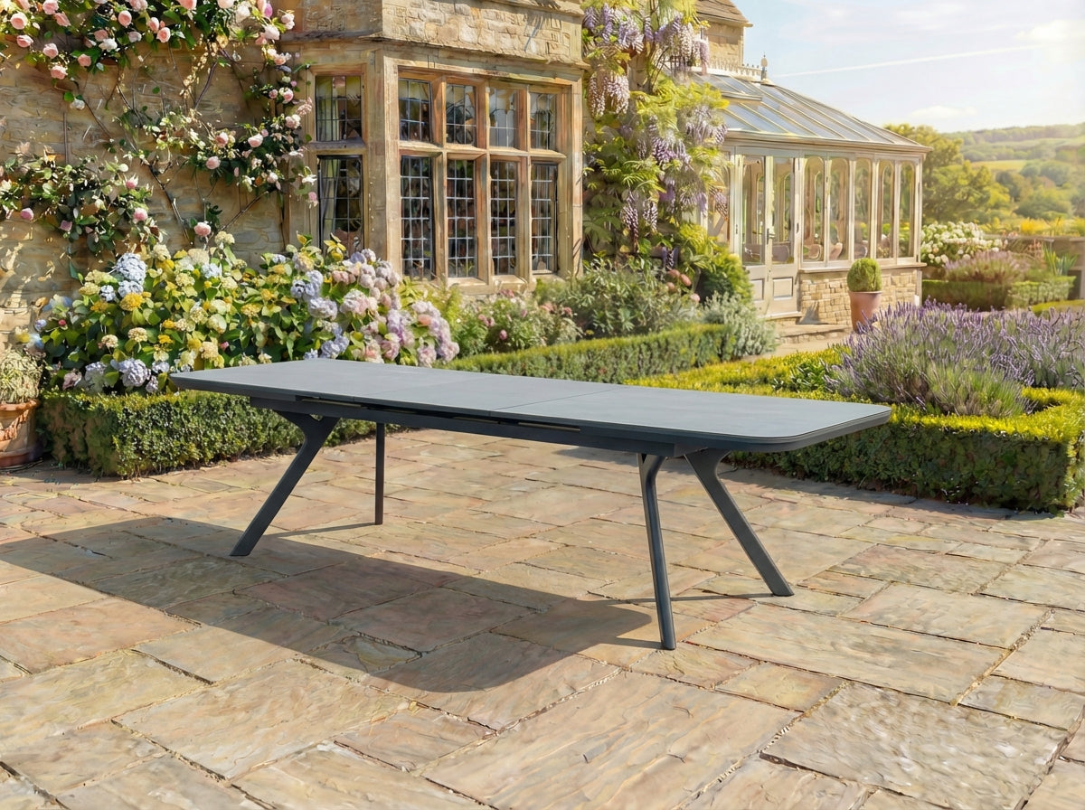 Outdoor ping pong table in a garden setting with a stone building and flowers in the background