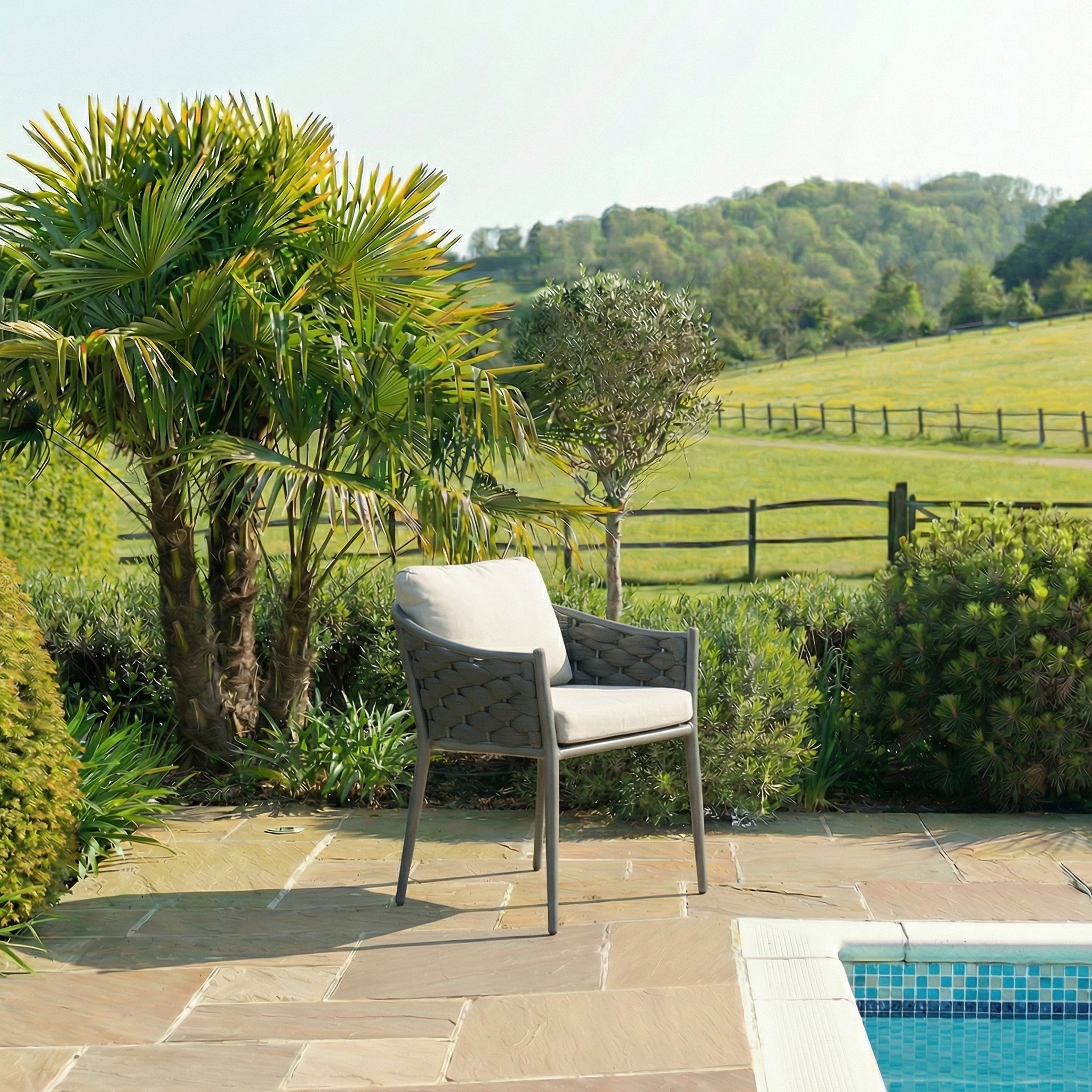 Chair by a pool with a scenic view of a field and trees