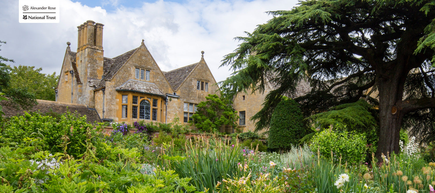 Stately home with a well-maintained garden and trees on a sunny day