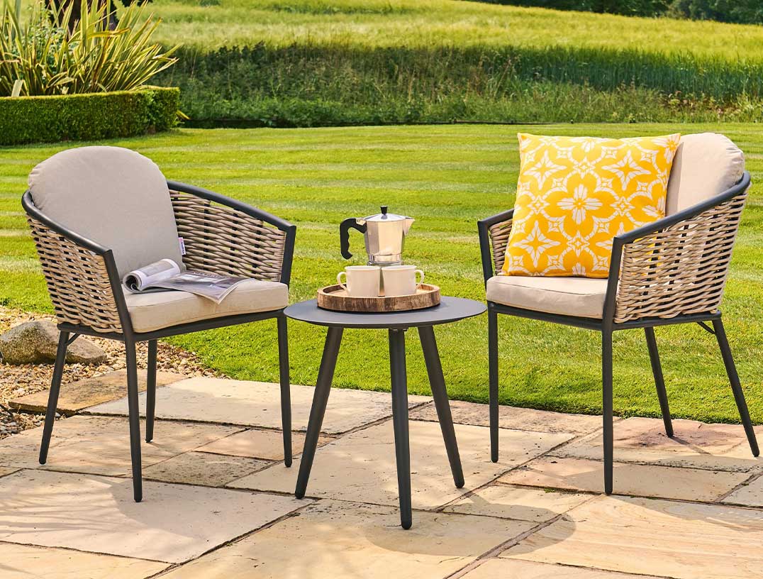Pavilion bistro set with two stylish dining chairs in rattan and black aluminium frame with small black coffee table.