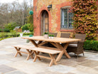 large plank table shown on an outdoor pation with 3 rattan chairs and two plank benches