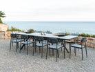 Rimini outdoor extending dining table with chairs on a stone patio by the sea