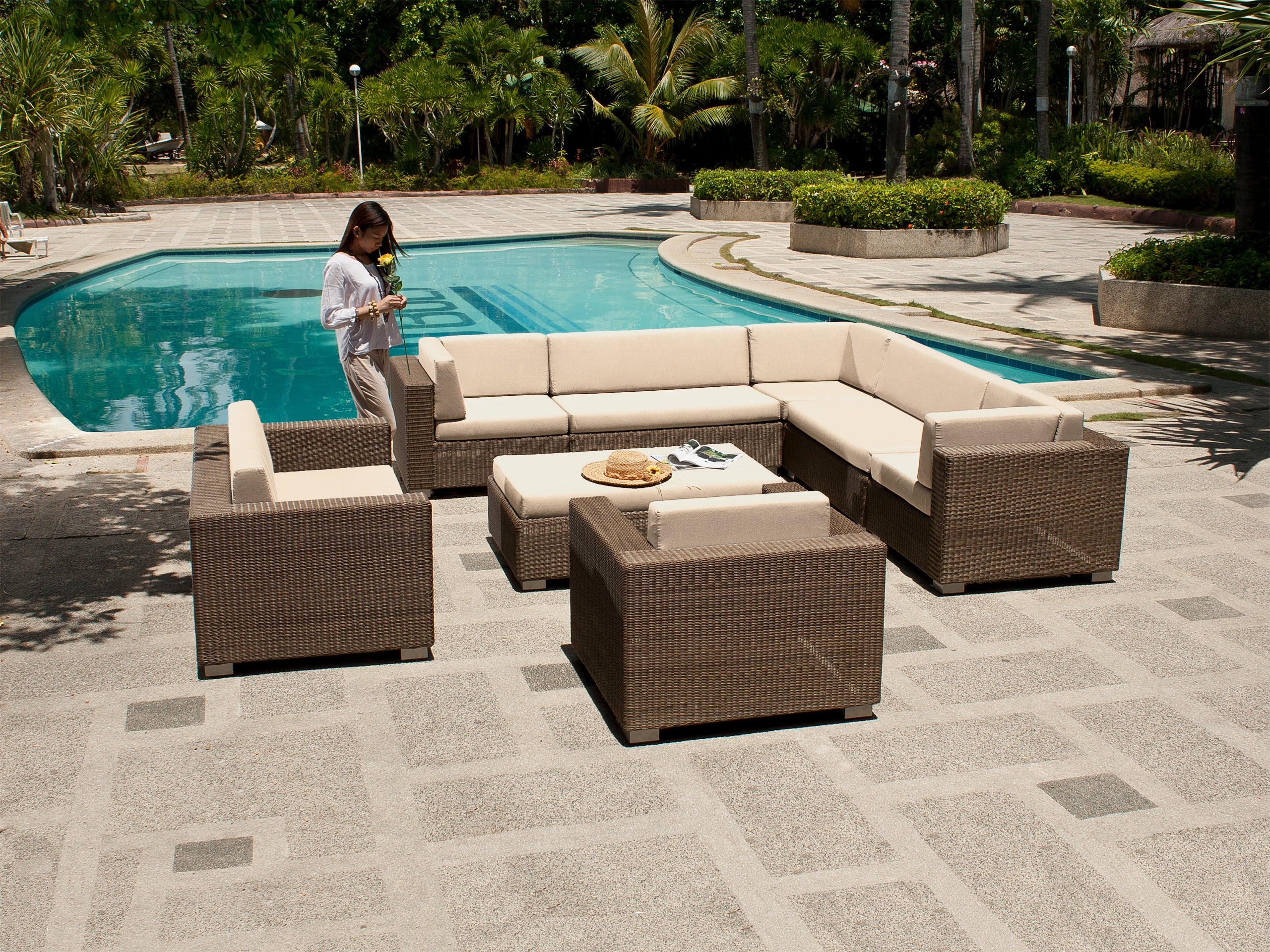 Outdoor patio furniture set by a pool with a person in the background.